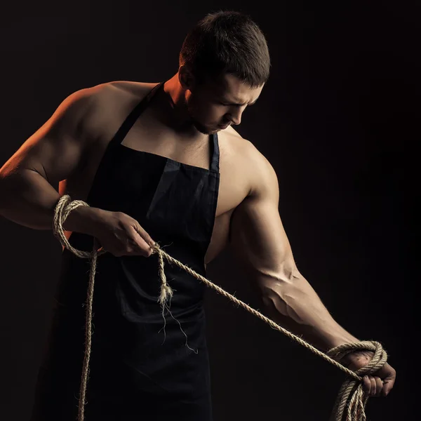 Muskulöser Mann in Schürze mit Seil — Stockfoto