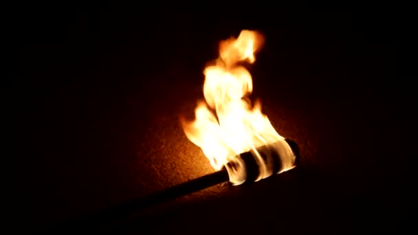 Горящий факел зажигается ночью, огонь делает красивую тень и дает свет в темноте — стоковое видео