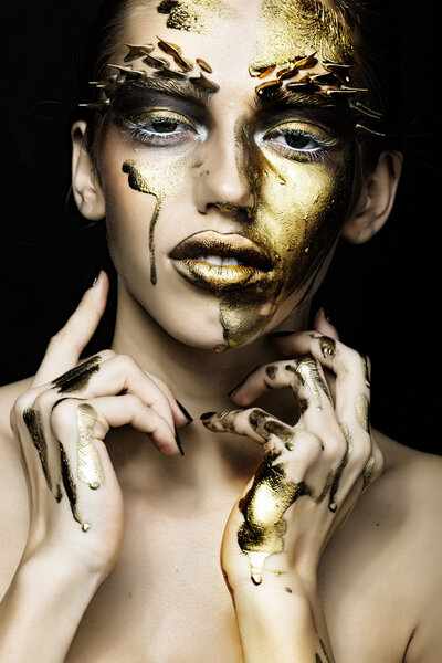 Closeup portrait of one beautiful sexy wild young woman with bright golden animal makeup with thorns on face in studio on black background, vertical picture