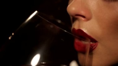 Kırmızı ruj siyah bir arka plan üzerinde gözlük closeup ile şarap içme ile kıvırcık kız