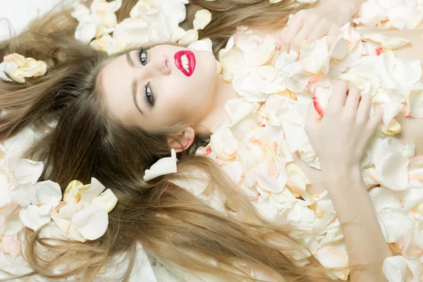 Mujer en pétalos de rosa — Foto de Stock