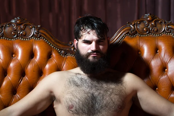 Bearded naked man on couch