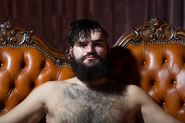 Bearded naked man on couch