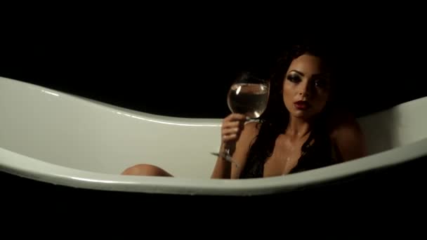 Junges Mädchen in der Badewanne gießt sich ein Glas Wasser über — Stockvideo