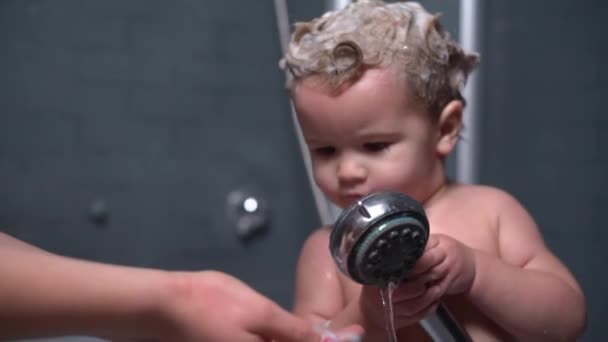 Cute beautiful baby with shampoo on the hair helps her mother to wash their hands — Stock Video