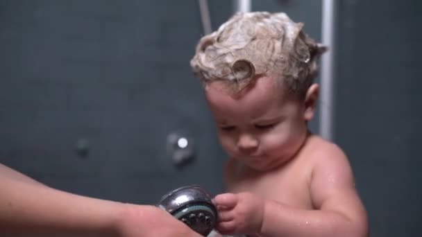 Cute beautiful baby with shampoo on the hair helps her mother to wash their hands — Stock Video