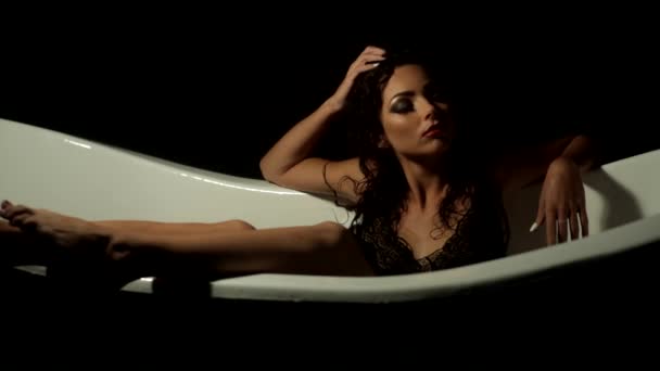 Sexy girl relaxes in the bath on a black background — Stock Video