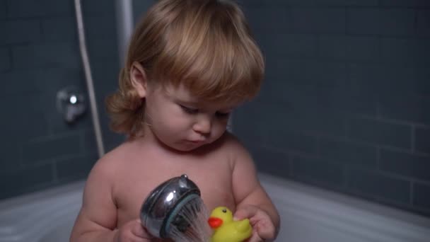 4 K Beautiful curly-haired boy in the shower pouring water toy duck — Stockvideo