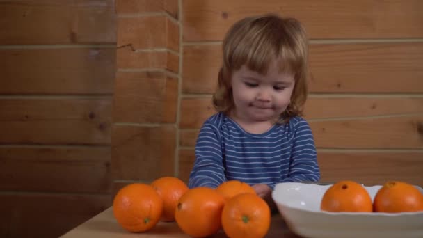 4K lindo menino encaracolado lendo uma receita em um telefone celular, "prepara" laranjas e bate palmas suas mãos — Vídeo de Stock