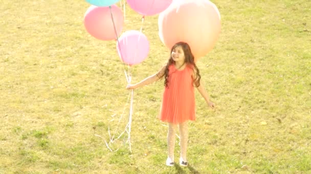 Mooi meisje op het gras spelen met ballonnen — Stockvideo