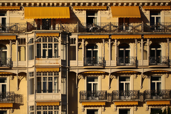 MONTREUX, SWITZERLAND - September 18, 2015: Beautiful ornate yellow building facade of Montreux Palace Hotel with balconies and sun awnings over windows, horizontal photo