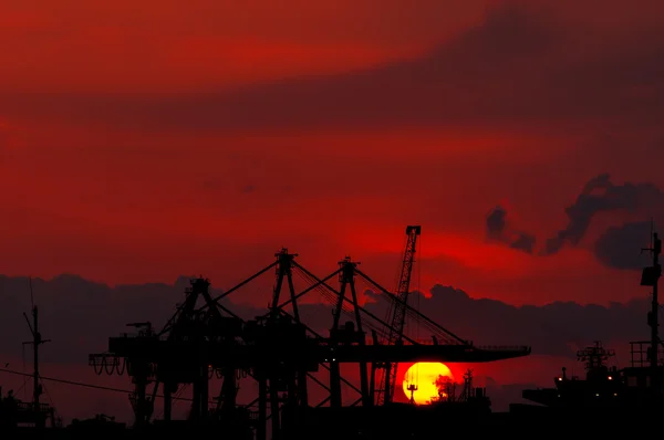 Silhouette of an Industrial Dock Crane Unloading at Sunset. Izmi