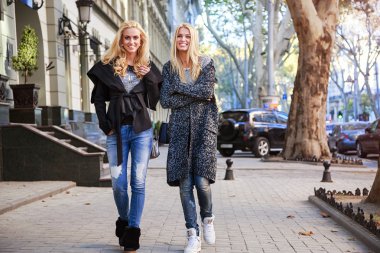 Outdoor portrait of stylish blonde sisters