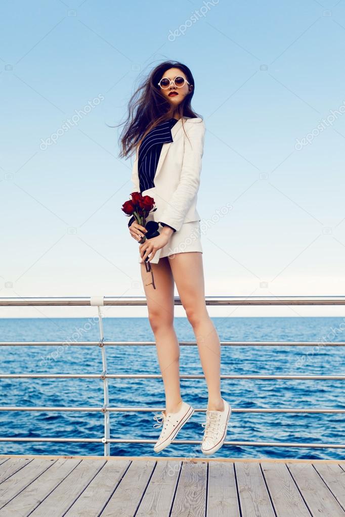 girl jumping at embankment with bouquet of roses