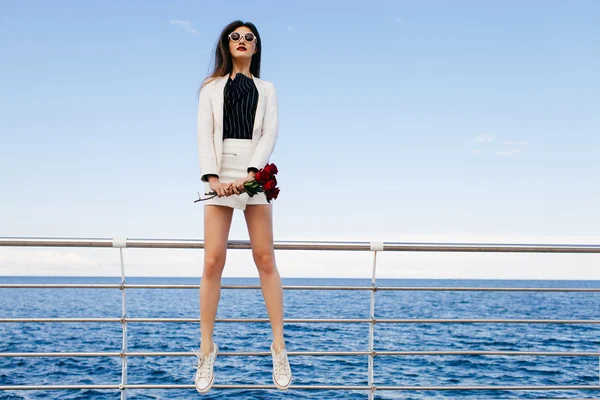 Chica saltando en terraplén con ramo de rosas — Foto de Stock