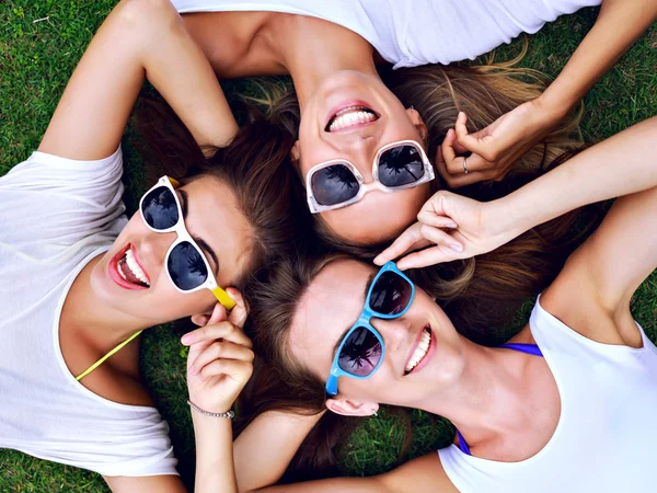 three hipster women laying on the grass