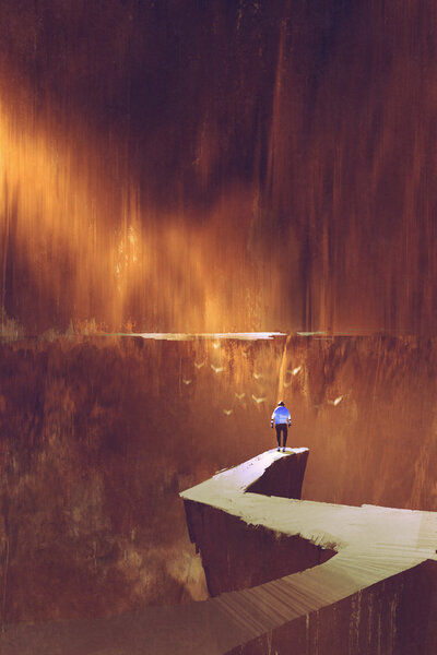 man standing on rock path looking at the mountain wall