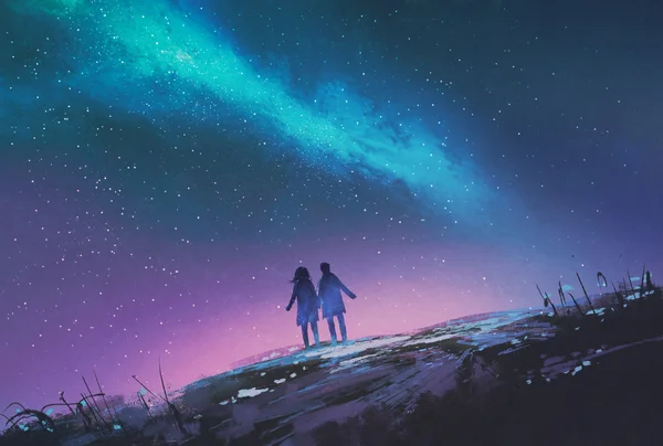 Pasangan muda berdiri berpegangan tangan terhadap galaksi Bima Sakti Stok Foto