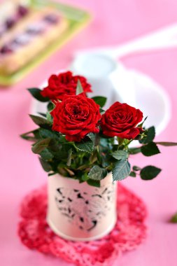 pembe bir arka plan üzerinde beyaz bir vazoda kırmızı güller