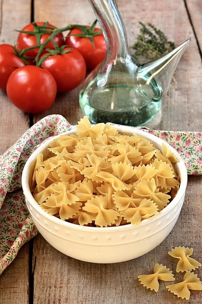 Pastas crudas en un bol con aceite de oliva y tomates — Foto de Stock