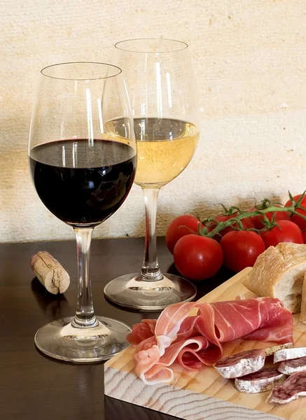 Червоне та біле вино у склянці з сосискою, помідорами та шинкою — стокове фото