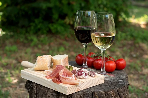 Червоне та біле вино у склянці з сосискою, шинкою та помідорами — стокове фото