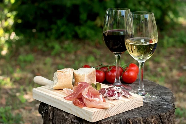 Red and white wine in a glass with sausage, ham and tomatoes — Stock Photo, Image