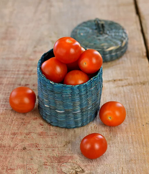 Cherry tomaten in een klein mandje op houten achtergrond — Stockfoto