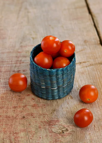 Cherry tomaten in een klein mandje op houten achtergrond — Stockfoto