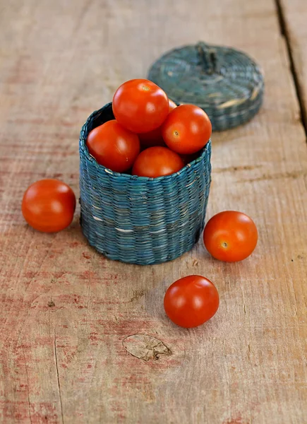 Cherry tomaten in een klein mandje op houten achtergrond — Stockfoto