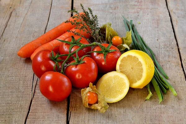 Tomaten, citroen, wortelen en physalis op houten achtergrond — Stockfoto