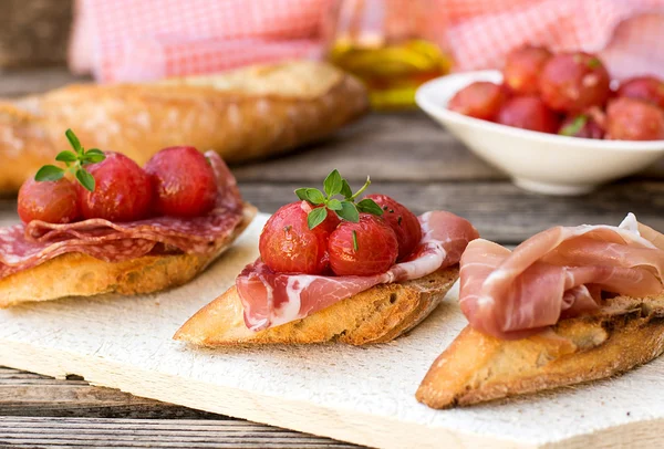 Italian bruschettas with ham prosciutto, coppa, salami, cherry t — Stock Photo, Image