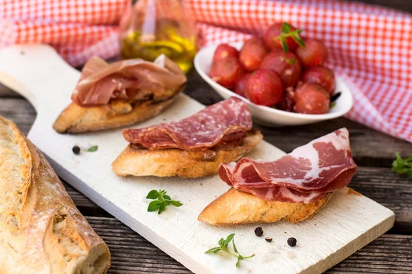 Italian bruschettas with ham prosciutto, coppa and salami — Stock Photo, Image