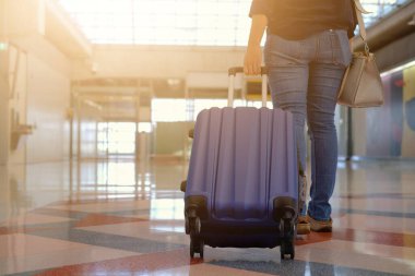 Arka plan, kot pantolonlu bir kadının, havaalanı terminalinde yürürken, mavi bavulunu arkaya çekerken, uçağına binmeye hazırlanırken....