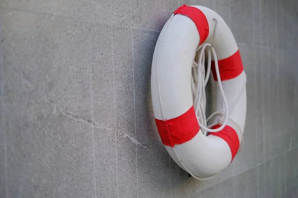 一条红白相间的救生绳 挂在游泳池边的墙上 以拯救溺水的游泳者 图库照片