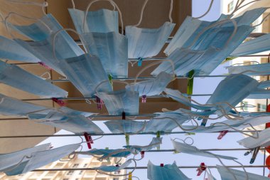 Mavi tek kullanımlık cerrahi maske yıkanmış ve kurutma askısına asılmış. Kişisel koruma ekipmanı eksikliği kavramı (PPE). Kriz zamanlarında yeniden kullanılabilirlik ve geri dönüşüm kavramı.