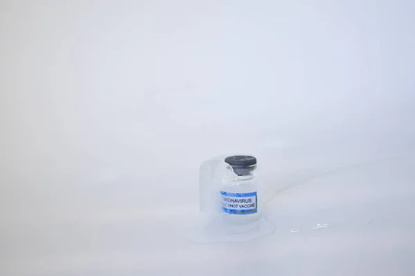Corona virüsü aşısı için çok düşük depolama sıcaklıklarına sahip Corona virüsü aşısı olan Glass şişesinin içinde dondurulmuş COVID aşısıyla yavaş yavaş eriyen buz küpü. Beyaz arkaplan, alanı kopyala