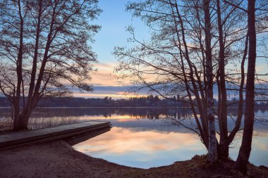 Nisan ayında Tuusula Gölü 'nün sakin renkli sularında bahar günbatımı.
