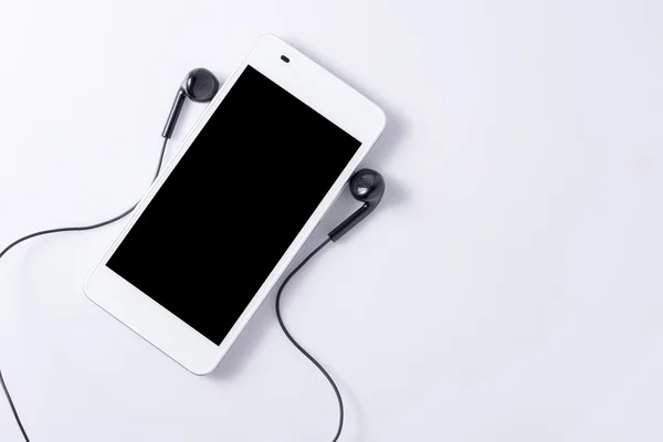 Мобильный телефон с наушниками на белом — стоковое фото