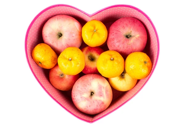 Laranja e maçã misturadas na caixa de presente em forma de coração no branco — Fotografia de Stock