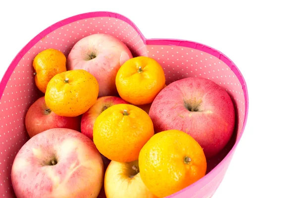 Laranja e maçã misturadas na caixa de presente em forma de coração no branco — Fotografia de Stock