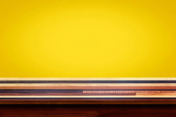 Pusty góry drewniany stół na żółtej ścianie gradientu tła. — Zdjęcie stockowe