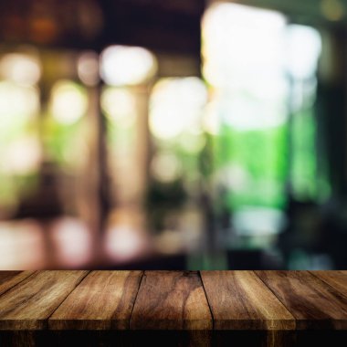 Arka planda bulanık oturma odası olan ahşap masanın üstü boş.