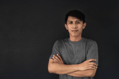 Siyah duvar arkasında gri tişörtlü Asyalı adam..