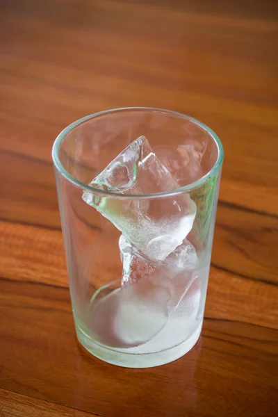 Um copo de cubos de gelo em madeira — Fotografia de Stock
