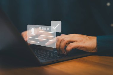 Dijital kimlik doğrulama ve kullanıcı kimlik doğrulama kavramı bir kişinin sanal kimlik kartı ile dizüstü bilgisayar kullandığını ve güvenli giriş, veri gizliliği ve hesap onayını simgeleyen işaretlemeyi gösterir.