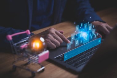 İnternetten alışveriş ve e-ticaret teknolojisini sembolize eden, arama ve alışveriş arabası simgelerinde dizüstü bilgisayar kullanan kişi. Dijital perakende, çevrimiçi pazar yeri ve elektronik ödeme sistemi kavramı.