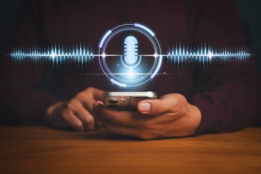 Ses tanıma teknolojisi bir kişinin parlayan bir mikrofon ikonu ve dijital ses dalgalarıyla akıllı telefon kullandığını gösteriyor. Yapay zeka asistanı, komut ve konuşma analizini sembolize ediyor..
