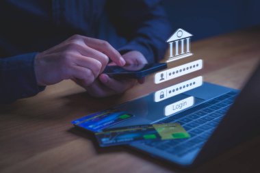 Bir dizüstü bilgisayarın üzerinde görüntülenen dijital giriş kartlı akıllı telefondan çevrimiçi bankacılığa erişim, güvenli işlemleri, finansal teknolojiyi, kimlik doğrulamayı ve dijital bankacılığı sembolize ediyor.