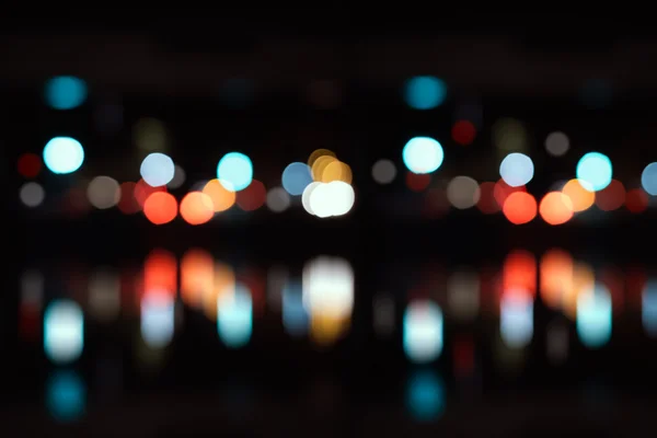 Verschwommene Stadtbeleuchtung mit Bokeh auf dem Wasser — Stockfoto